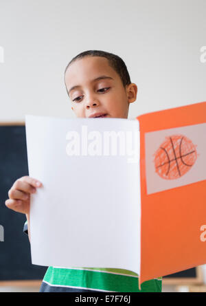Mestizos chico leyendo informe sobre baloncesto en clase