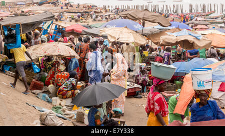 Mbour, Senegal - Julio, 2014: Varios centenares de personas se reúnen en el mercado de pescado local en Mbour para comprar y vender el diario de ca Foto de stock