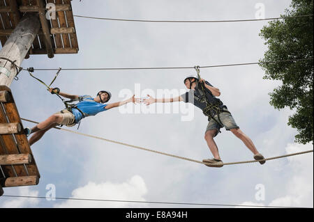 Adolescente en una escalada risco ayudando a otro Foto de stock