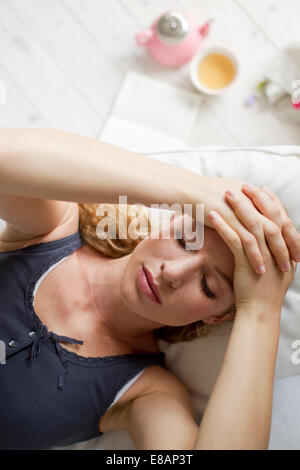 Mujer recostada en el sofá con las manos en la cabeza. Foto de stock