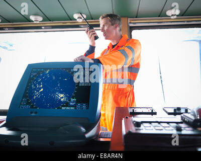 Trabajador del barco en el puente utilizando un walkie-talkie