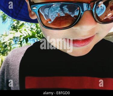 Retrato de un niño parado en una piscina infantil con gafas de sol