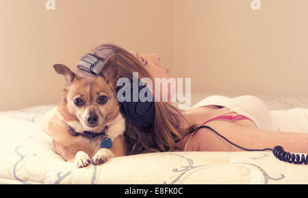 Una joven acostada en la cama con su perro Foto de stock