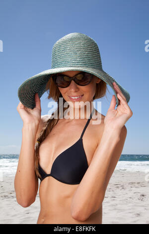 Mujer joven en la playa con sombrero de paja, Ciudad del Cabo, Cabo Occidental, Sudáfrica