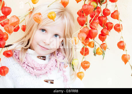 Retrato de una chica sonriente de pie junto a una planta de faroles chinos