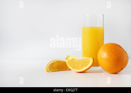 Vaso de jugo de naranja con naranjas frescas Foto de stock