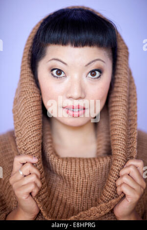 Mujer asiática con cálidos fuzzy suéter de cuello del salpicadero. Corte de pelo corto con flequillo lindo.