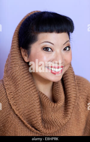 Mujer asiática con cálidos fuzzy suéter de cuello del salpicadero. Corte de pelo corto con flequillo lindo.