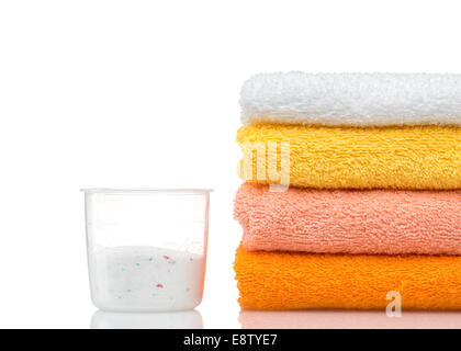 Detergente para lavadora en lavadero con toallas en el fondo blanco. Foto de stock