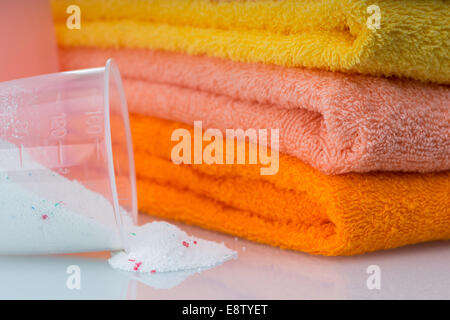 Detergente para lavadora en lavadero con toallas en el fondo blanco. Foto de stock