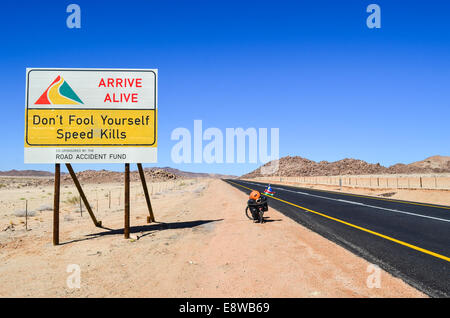 Señal de seguridad en carretera en el sur de África, El Cabo Septentrional, la lectura "no te engañes, la velocidad mata' y una bicicleta Foto de stock