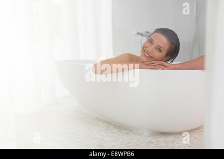 Mujer sonriente de tomar un baño en el cuarto de baño moderno Foto de stock