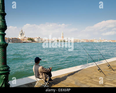 Un pescador esperando pacientemente para pescar, con vistas al Canale della Giudecca en Venecia, Italia.