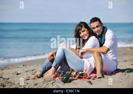 Pareja joven disfrutando de un picnic en la playa