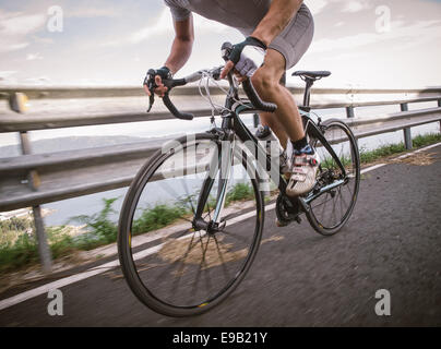 Detalle de una bicicleta de carretera con un ciclista pedaleando en una carretera.
