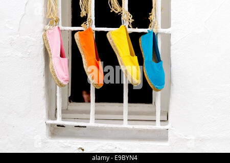 Cuatro colores brillantes zapatos tradicionales españolas colgando fuera de una ventana Foto de stock