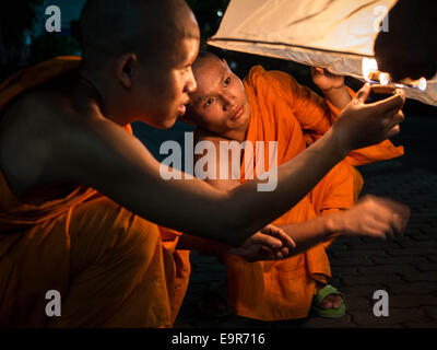 Dos monjes budistas, naranja-revestido de papel de arroz, la iluminación de un globo de aire caliente en el Festival Loy Krathong en Chiang Mai, Tailandia. Foto de stock