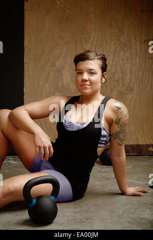 Retrato de mujer joven sentada en el suelo del gimnasio