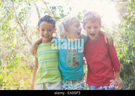 Tres niños en el jardín con los brazos alrededor de cada una de las otras