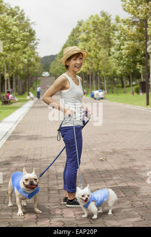 Mujer caminar dos perros en un camino pavimentado.