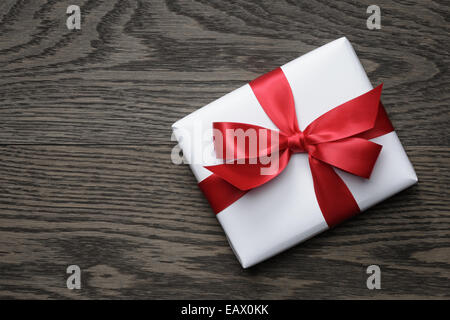 Caja de regalo con lazo rojo sobre la mesa de madera, vista superior