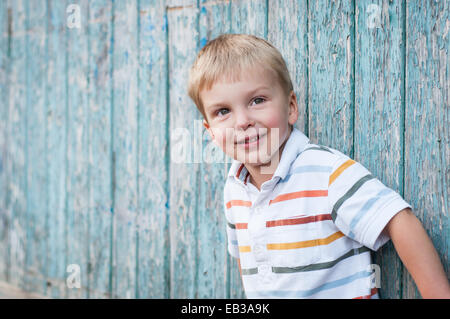 Retrato de niño recostado contra la pared de madera