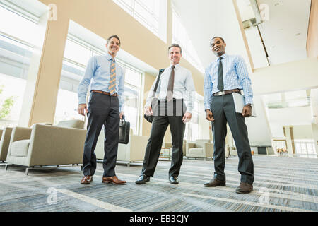 Ángulo de visión baja de empresarios sonriendo en la oficina vestíbulo