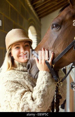 Mujer sonriente acariciando la cabeza del caballo