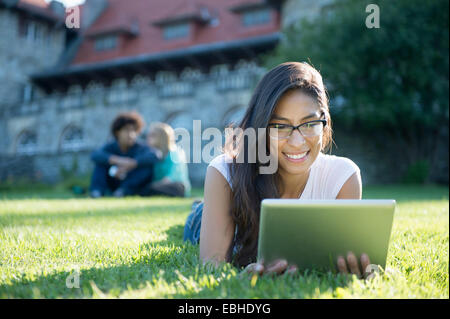 Mujer joven acostado sobre el césped utilizando tablet digital Foto de stock