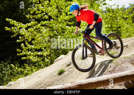Hembra joven ciclista de BMX aceleración rocas en el bosque Foto de stock