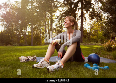 Mujer adulta media sentado en el parque tomando ejercicio romper