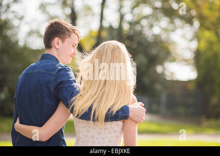 Vista trasera de la romántica pareja joven paseando en el parque Foto de stock
