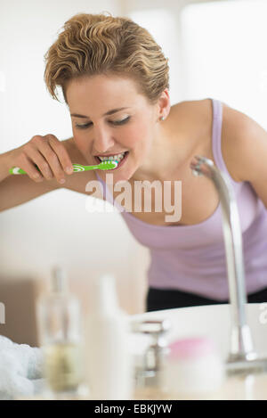 Mujer joven cepillarse los dientes en el baño. Foto de stock