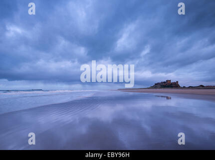 Stormclouds reflexionar sobre la desierta playa al lado de Bamburgh Castle, Northumberland, Inglaterra. Invierno (marzo de 2014).