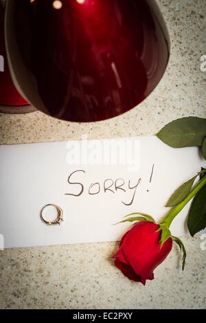 Concepto de perdida de relación con una carta, una rosa roja y un anillo de compromiso en una mesa izquierda Foto de stock