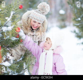Madre e hijo de familia feliz jugando con árbol de navidad decoración exterior