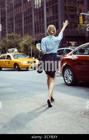 Mujer caucásica aclamar taxi en calle urbana