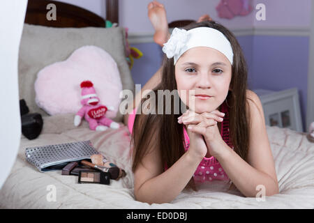 Retrato de una niña acostada en la cama con el maquillaje Foto de stock