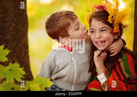 Niño tratando de besar a una chica en el bosque Foto de stock