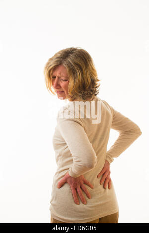 En la parte baja de la espalda dolor lumbar- Una mujer caucásica de  cuarenta años con dolor de espalda, dolor de espalda, frotando su espalda  baja de masaje para aliviar el dolor, contra un fondo blanco. UK Fotografía  de stock - Alamy