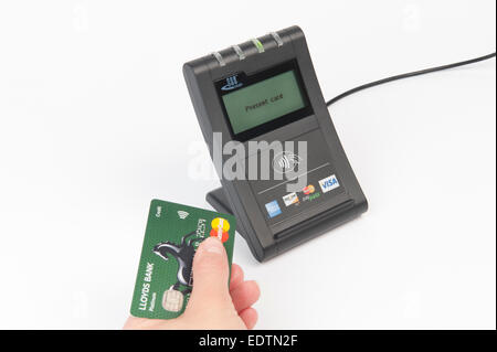 Mano sujetando la tarjeta Mastercard de pago sin contacto con lector de tarjeta Foto de stock