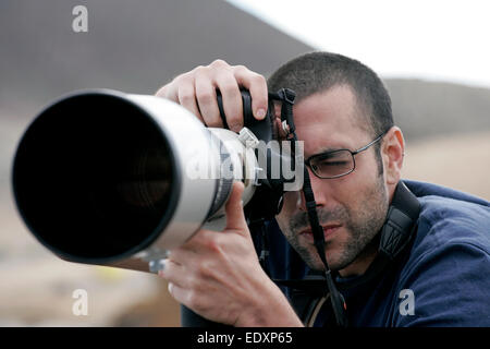 Fotógrafo gafas utiliza un teleobjetivo Canon largo Foto de stock