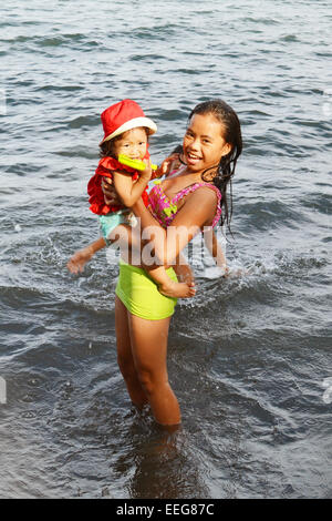 Poco de Asia chica asustada del agua mientras que su hermana se está riendo Foto de stock