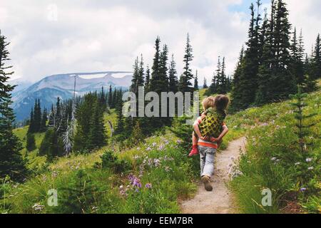 Niño caminando a lo largo de un sendero de montaña dando a su hermana un paseo en piggyback, Estados Unidos