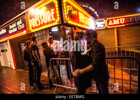 Dos jóvenes besándose , pareja, chico chica, fuera 'Pier' presión night club discoteca en la víspera de año nuevo en la lluvia Gales Aberystwyth UK Foto de stock