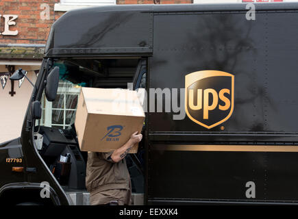Entrega de paquetes UPS van con conductor llevando un gran paquete Foto de stock
