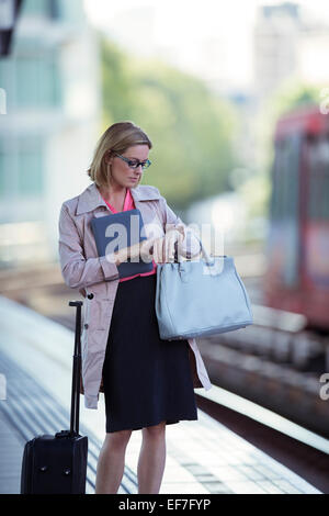 La empresaria comprobando su reloj en la estación de tren Foto de stock
