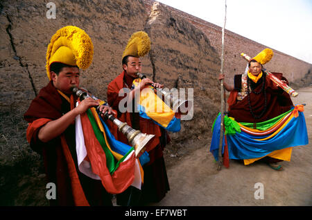 China, Tíbet, provincia de Qinghai, Tongren (Repkong), monasterio de Wutun Si, día del año nuevo tibetano, monjes tocando la trompeta tradicional Foto de stock