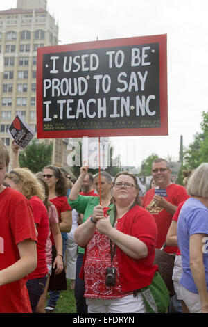 En Asheville, Carolina del Norte, Estados Unidos de América - agosto 4, 2014: un maestro y otros sostienen pancartas protestando el estado de la educación pública de NI Foto de stock