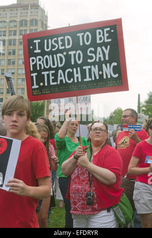 En Asheville, Carolina del Norte, Estados Unidos de América - agosto 4, 2014: un maestro y otros sostienen pancartas protestando el estado de la educación pública de NI Foto de stock